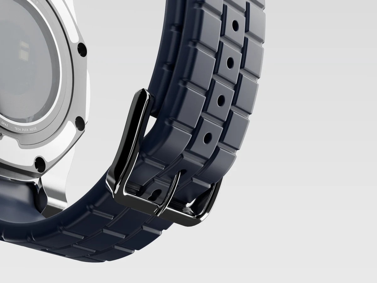 Close-up of the steel pin buckle and the strap's block pattern, with a tang hole in every centre block.